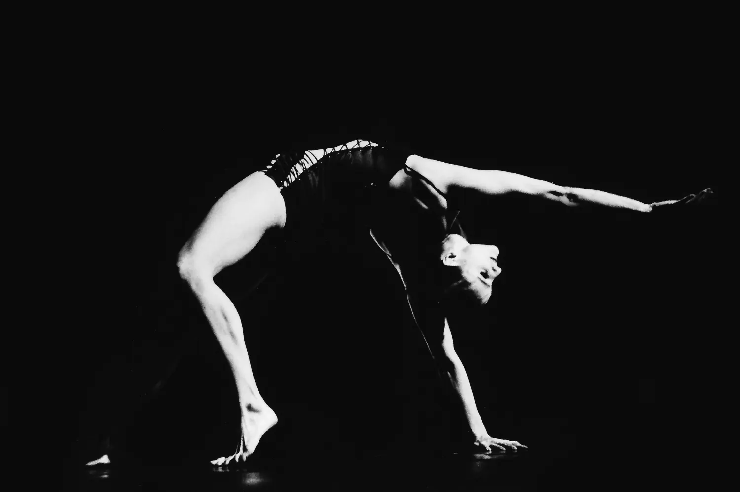 Bailarina arqueada hacia atrás sobre fondo negro