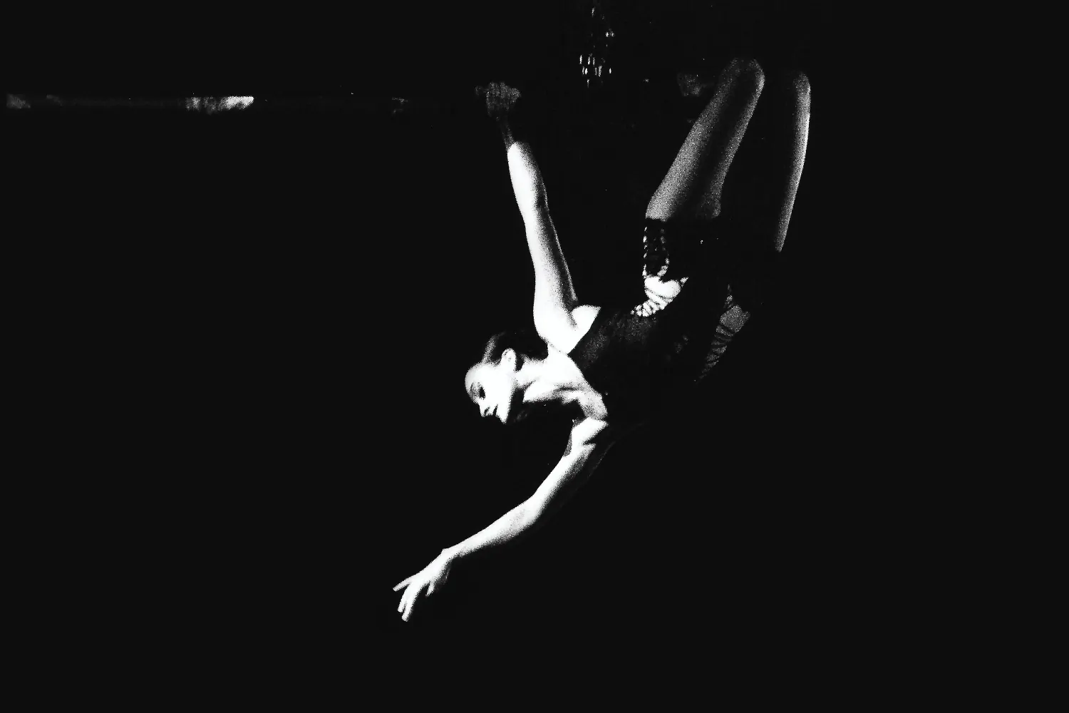 Bailarina aérea colgada de cabeza con un brazo extendido